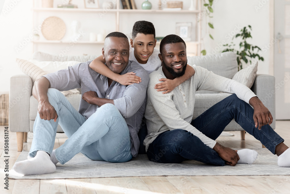 Portrait of happy preteen afro boy hugging father and grandpa at home