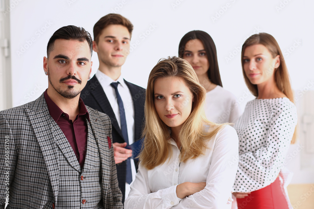 Group of smiling people stand in office looking in camera Group of smiling people stand in office looking in camera