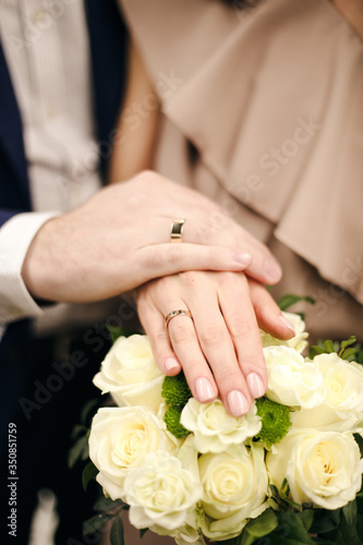 The joined hands of the bride and groom at a wedding. Wedding rings on the fingers of the newlyweds. Hands close up. 