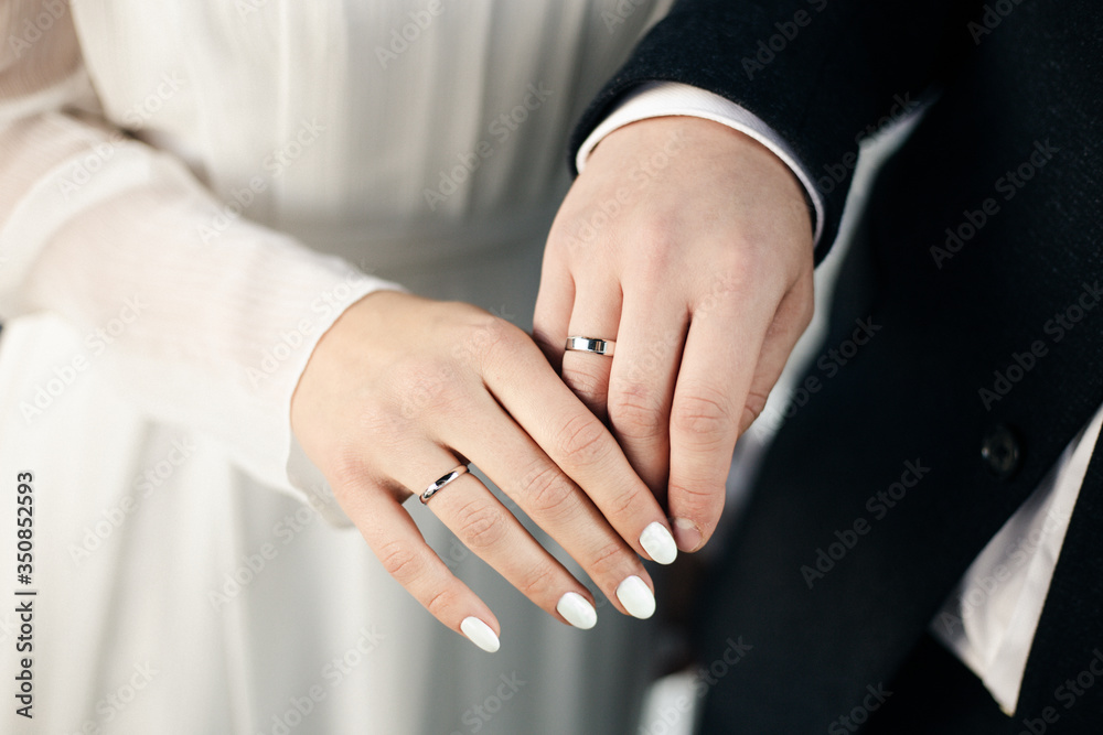 The joined hands of the bride and groom at a wedding. Wedding rings on the fingers of the newlyweds. Hands close up. The joined hands of the bride and groom at a wedding. Wedding rings on the fingers of the newlyweds. Hands close up.