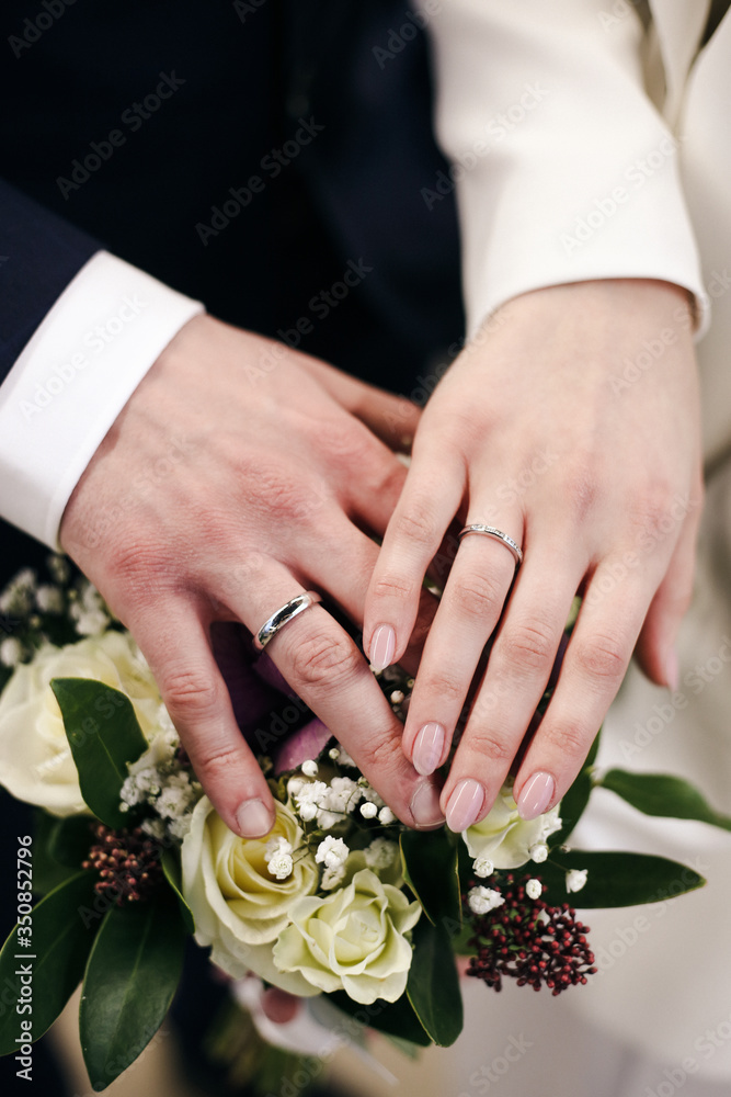 The joined hands of the bride and groom at a wedding. Wedding rings on the fingers of the newlyweds. Hands close up. The joined hands of the bride and groom at a wedding. Wedding rings on the fingers of the newlyweds. Hands close up.