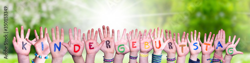 Children Hands Building Colorful German Word Kindergeburtstag Means Childrens Birthday Party. Sunny Green Grass Meadow As Background