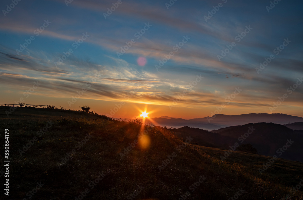 Sunrise in the mountains with orange and blue sky and silhouettes of the mountains