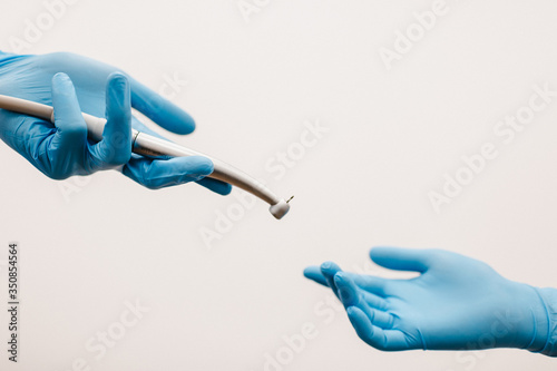 Dental instrument in hand on a white background. Dental clinic hygiene. Two hands in blue gloves.