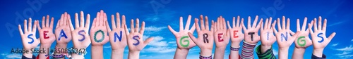 Children Hands Building Colorful English Word Seasons Greetings. Blue Sky As Background