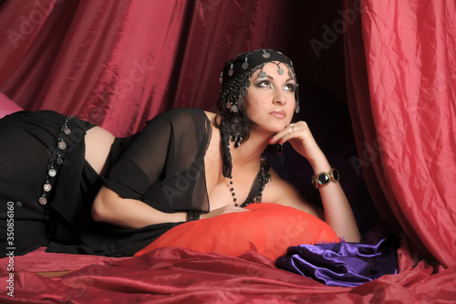 eastern woman in black clothes lies on pillows photo