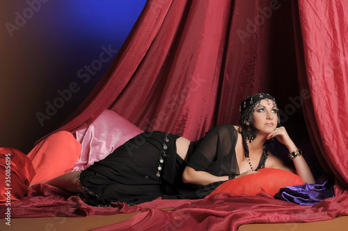 eastern woman in black clothes lies on pillows photo