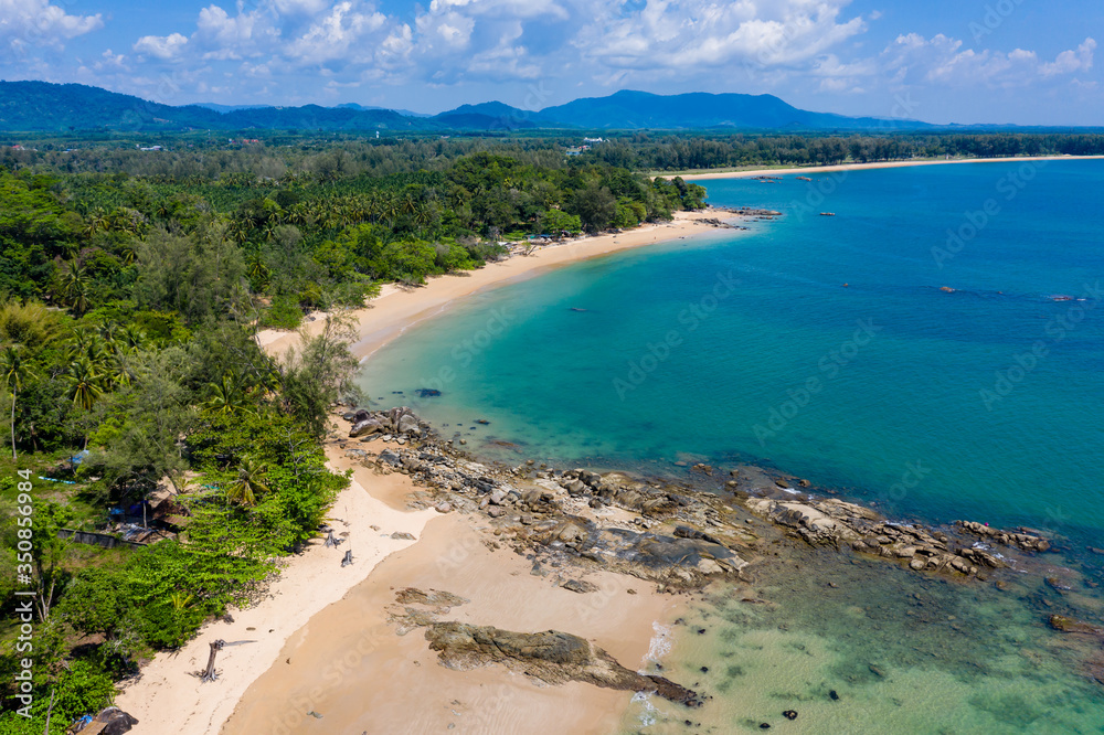 Aerial view of a beautiful, empty tropical beach surrounded by lush green foliage