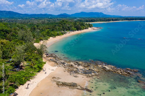 Aerial view of a beautiful, empty tropical beach surrounded by lush green foliage