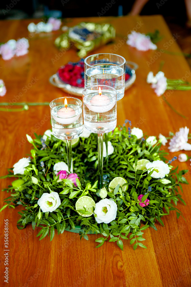 preparation for a master class in floristry. Table decor elements (wreath of fresh plants and citruses, burning candles)