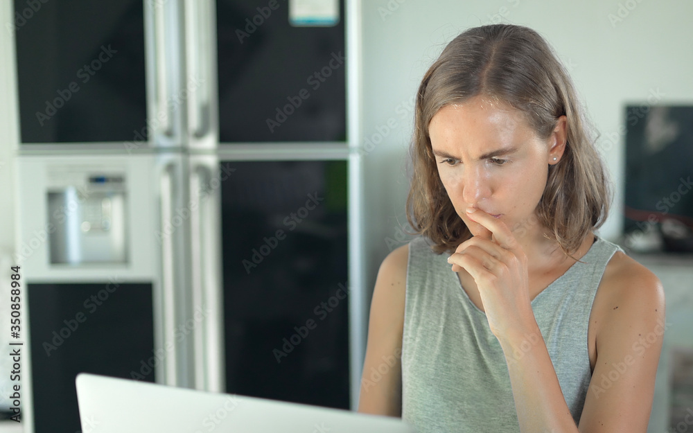 Blonde girl with serious upset face looking at laptop computer screen display
