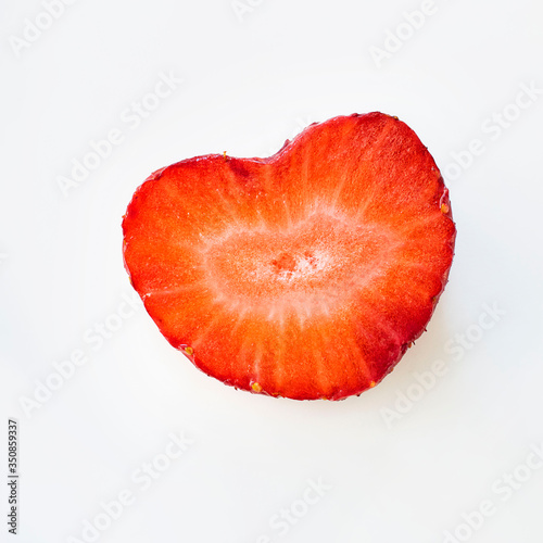 Isolated close up heart shape ripe red strawberry cut in half on a white background. Macro square image about fresh organic berries, harvets, healthy food and vitamin C