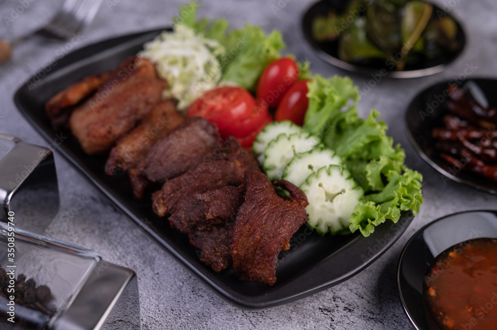 Fried pork topped with sesame placed in a black dish. Fried pork topped with sesame placed in a black dish.