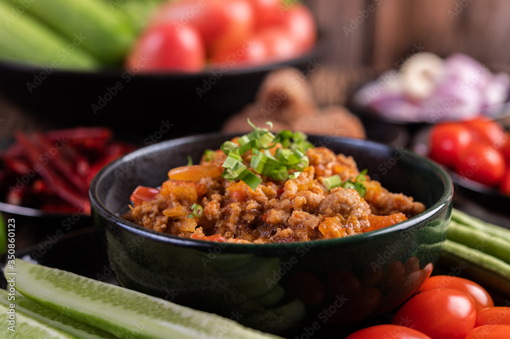 Sweet pork in a black bowl, complete with cucumbers, long beans, tomatoes, and side dishes Sweet pork in a black bowl, complete with cucumbers, long beans, tomatoes, and side dishes