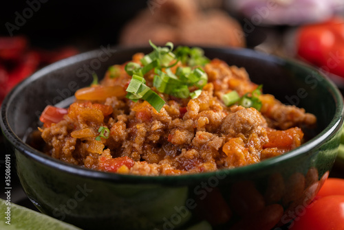 Sweet pork in a black bowl, complete with cucumbers, long beans, tomatoes, and side dishes © Johnstocker