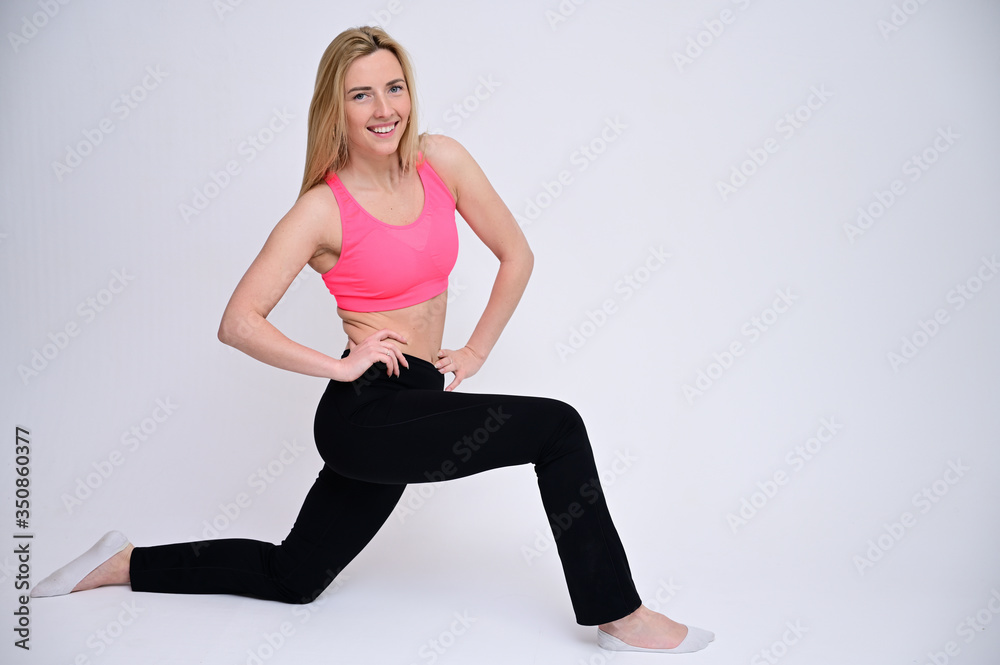 Portrait of a pretty fitness blonde girl in a sports uniform on a white background is doing exercises. A slender Caucasian model poses with a smile. Portrait of a pretty fitness blonde girl in a sports uniform on a white background is doing exercises. A slender Caucasian model poses with a smile.