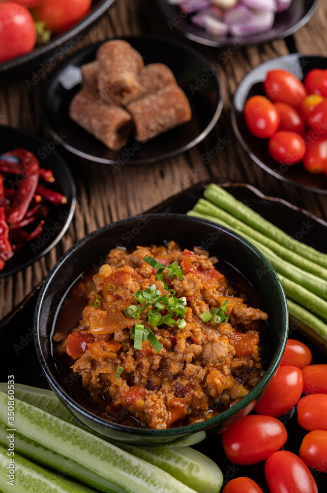 Sweet pork in a black bowl, complete with cucumbers, long beans, tomatoes, and side dishes Sweet pork in a black bowl, complete with cucumbers, long beans, tomatoes, and side dishes