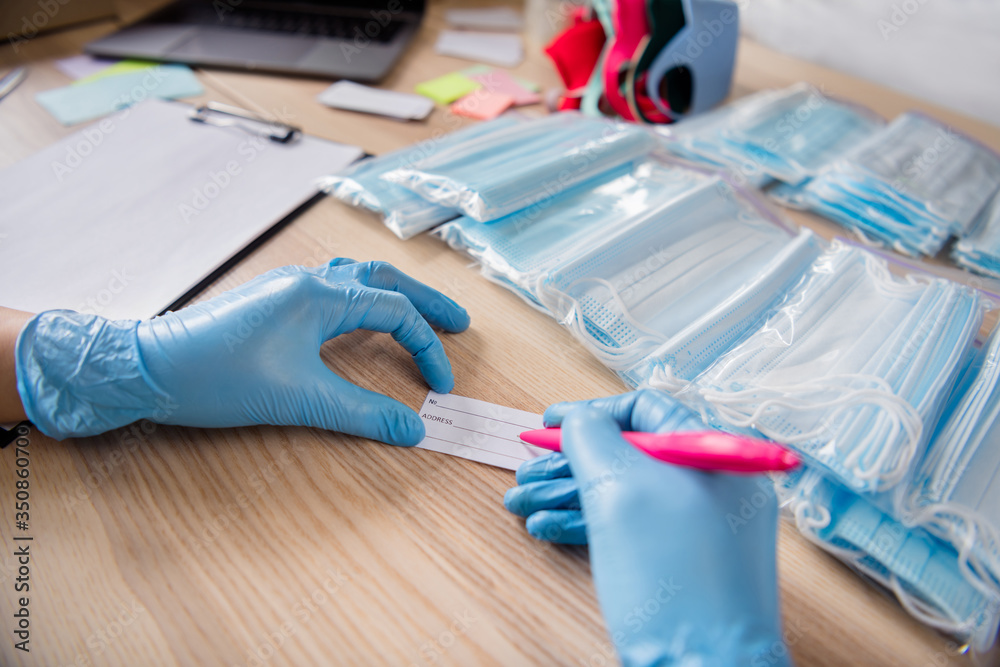 Cropped photo of lady hands latex gloves trend business organizing face flu medical masks own product packages write order check customer address prepare sets delivery home office indoors Cropped photo of lady hands latex gloves trend business organizing face flu medical masks own product packages write order check customer address prepare sets delivery home office indoors