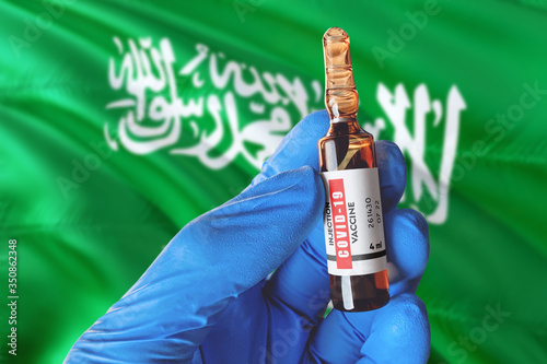 Saudi Arabia flag with Coronavirus Covid-19 concept. Doctor with blue protection medical gloves holds a vaccine bottle. coronavirus covid 19 vaccine research.
