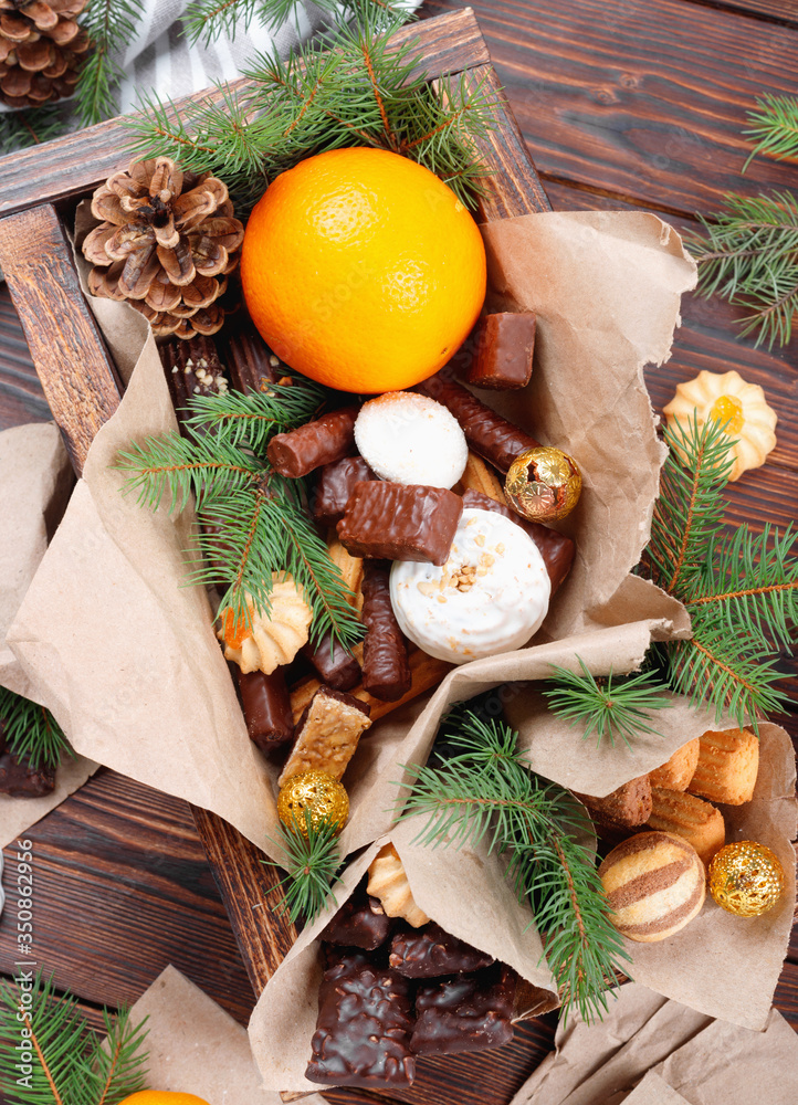 Delicious sweets, chocolates, cookies and oranges for gifts in wooden box on vintage table Delicious sweets, chocolates, cookies and oranges for gifts in wooden box on vintage table