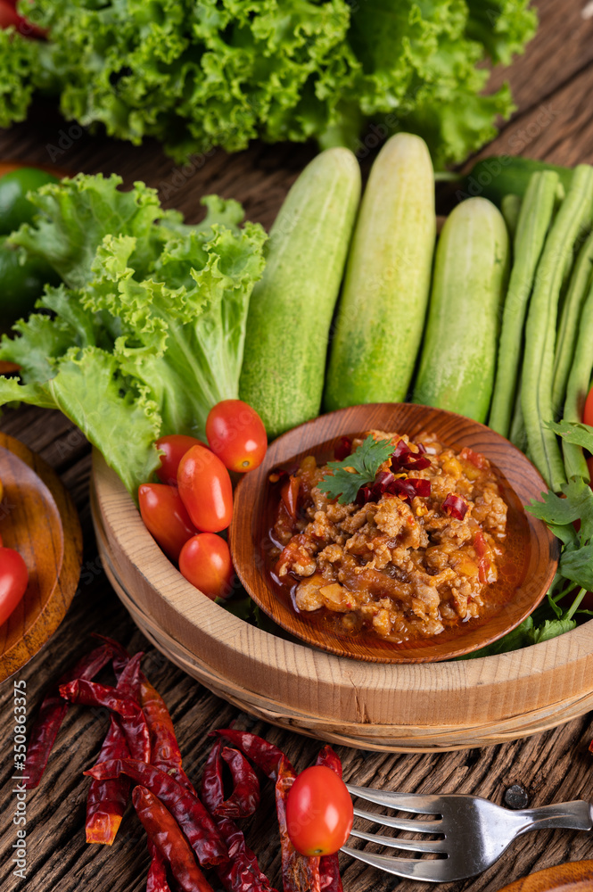 Sweet pork in a wooden bowl with cucumber, long beans, tomatoes, and side dishes. Sweet pork in a wooden bowl with cucumber, long beans, tomatoes, and side dishes.