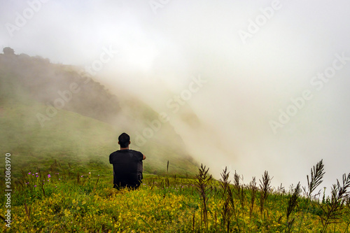 man isolated feeling the serene nature at hill top with amazing cloud layers in foreground © explorewithinfo