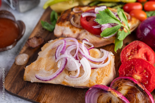 Chicken steak placed on a wooden tray.