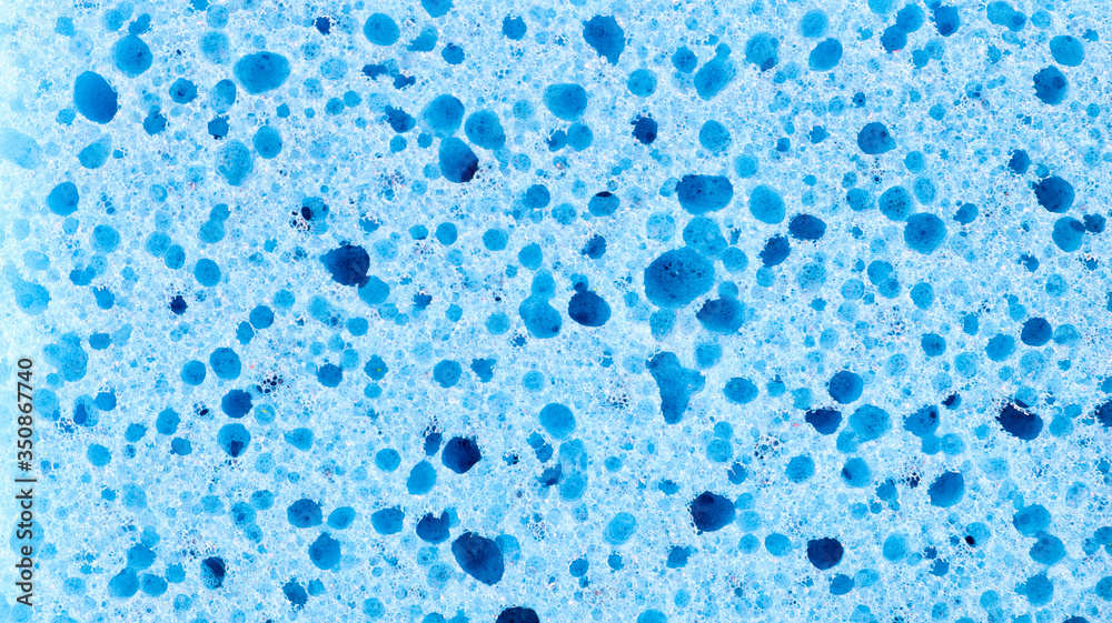 Background in the form of a porous structure in blue. Macro sponge. Close up blue sponge surface for textured background. copy space.