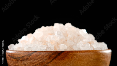 pink Himalayan salt in wooden bowl. black background macro