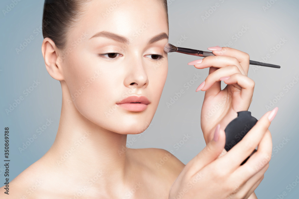 Young woman is applying eye makeup