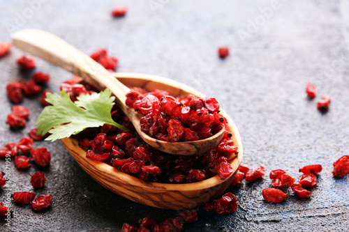 Pile of dry barberries in a wooden bowl on rustic table