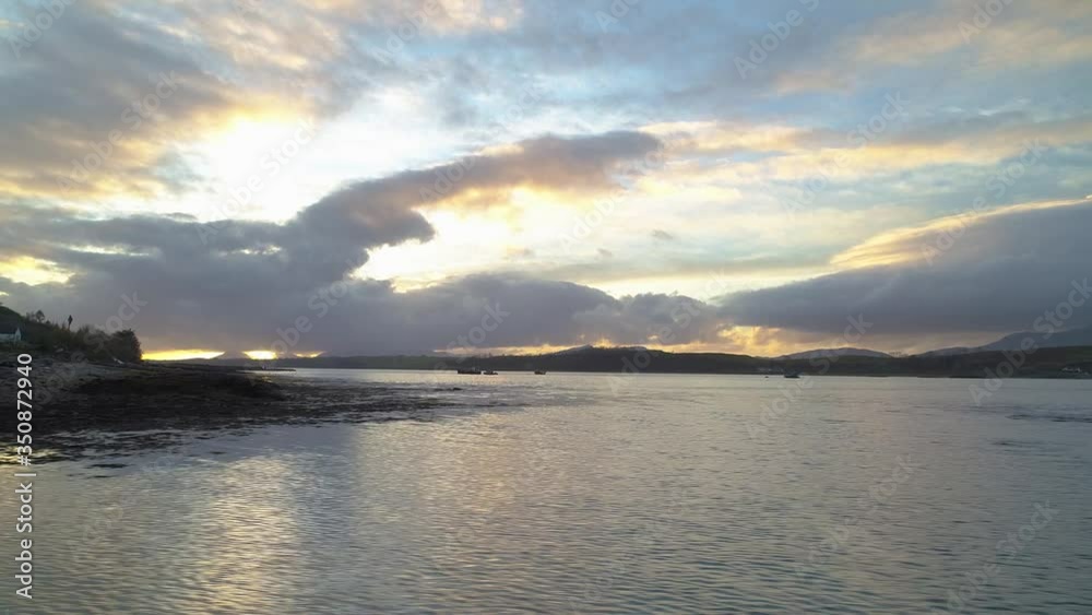 Fast and low aerial movement from coastline out to sea looking toward colourful sunset, Scotland UK Fast and low aerial movement from coastline out to sea looking toward colourful sunset, Scotland UK