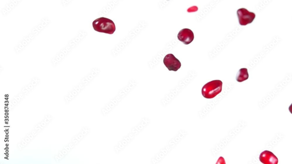 Shiny grains of ripe pomegranate are flying diagonally on a white background in slow motion, loop footage Shiny grains of ripe pomegranate are flying diagonally on a white background in slow motion, loop footage