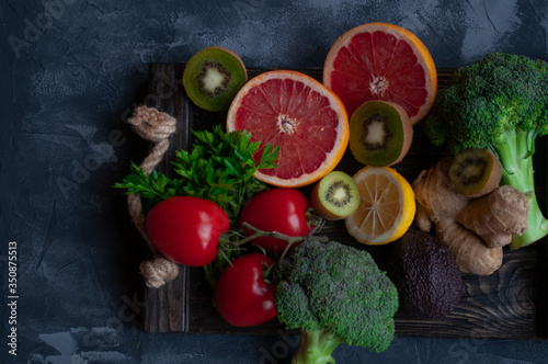 Fresh fruits and vegetables background. Healthy food on wooden tray.