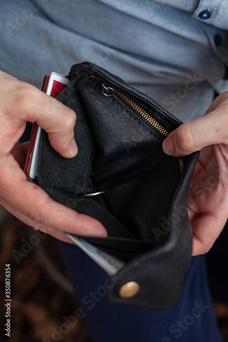 men's hands hold an empty purse. A wallet with little money in it. The concept of poverty and bankruptcy