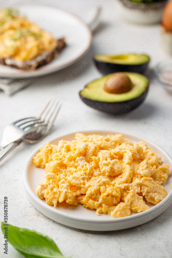 Fresh cooked scrambled eggs in a plate on white background.