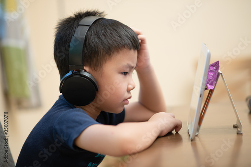 Asian male child doing online learning or e-learning at home