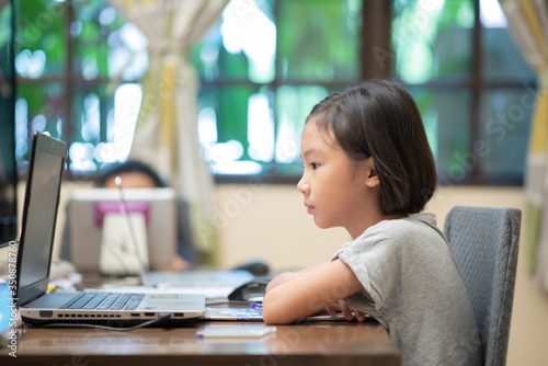 Asian female child doing online learning or e-learning at home