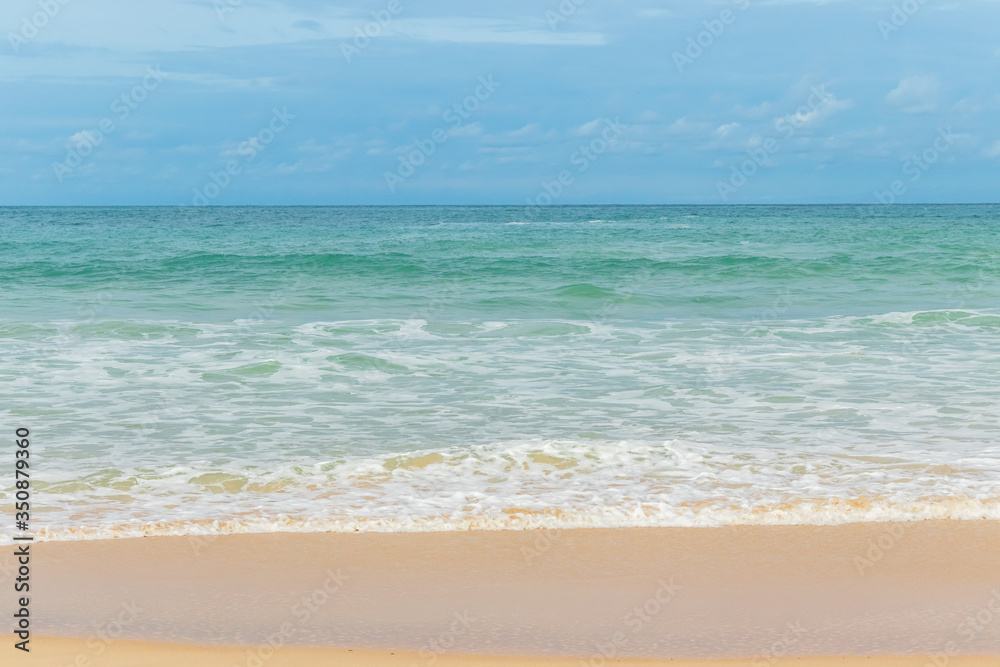 sandy beach blue sky and white formy wave