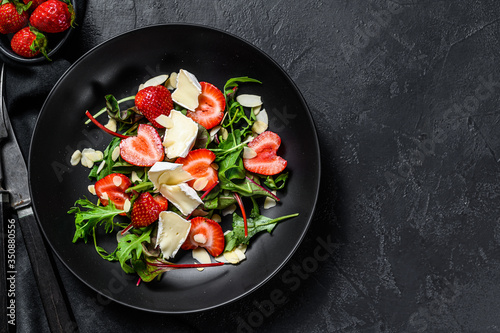 Healthy delicious salad with Camembert, strawberries, nuts, chard and arugula. Black background. Top view. Copy space
