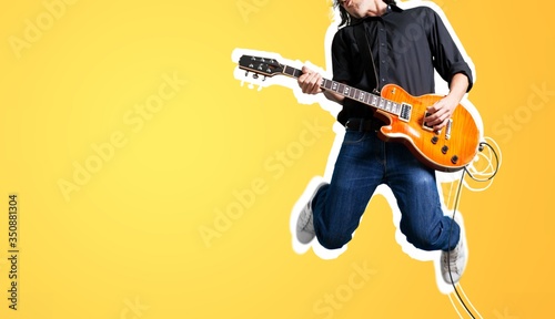 Fotografiet Male guitarist playing music and jump