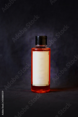 orange oil bottle with off white label and black bottle cap on dark grey textured background.