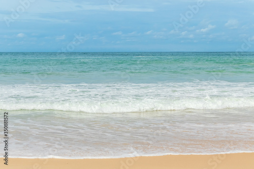 sandy beach blue sky and white formy wave