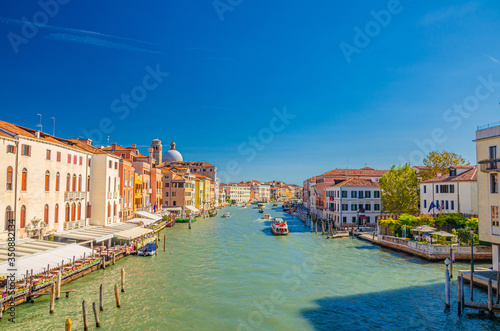 Venice cityscape with Grand Canal waterway. View from Scalzi bridge. Gondolas, boats, yachts, vaporettos docked and sailing Canal Grande. Venetian architecture buildings. Veneto Region, Italy. © Aliaksandr