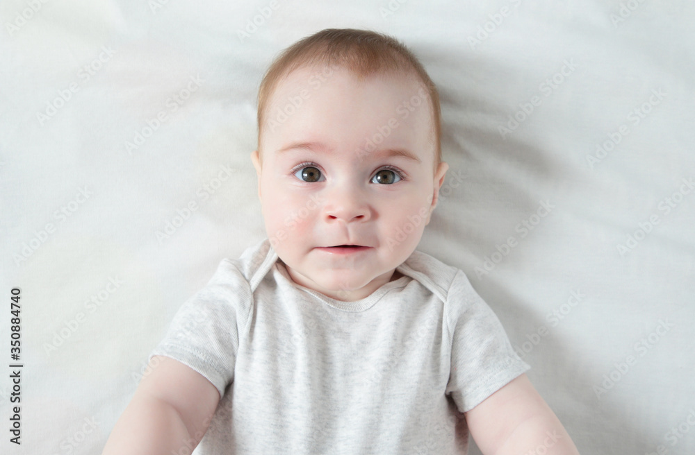 Peaceful baby lying on a white bed , top view Peaceful baby lying on a white bed , top view