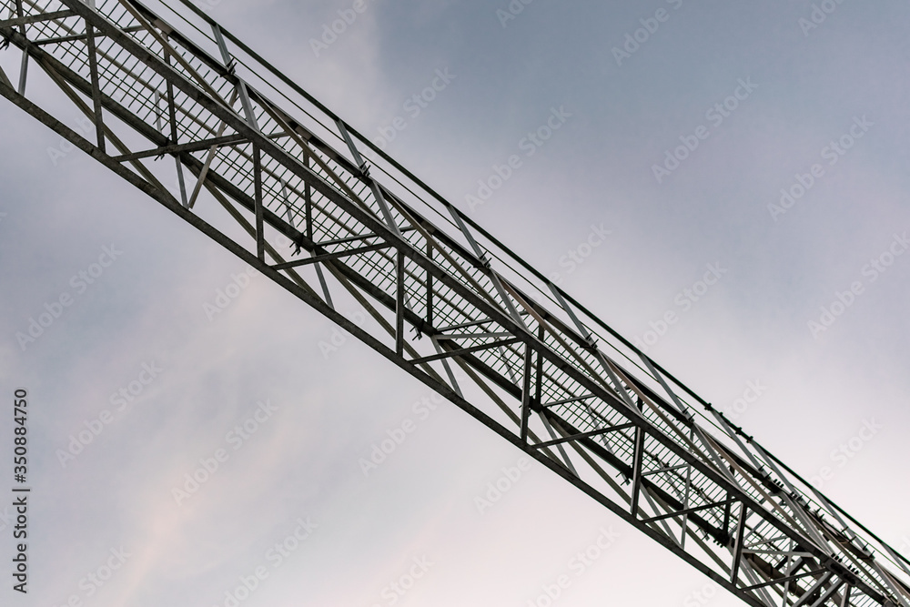 High and narrow bridge at the railway station. For crossing over tracks and trains. A long bridge with steps in the evening at sunset.
High and narrow bridge at the railway station. For crossing over tracks and trains. A long bridge with steps in the evening at sunset.