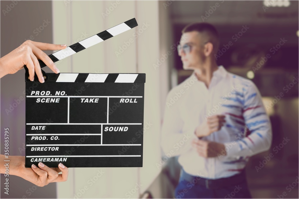 Hands holding film clapper board with an actor on background - obrazy, fototapety, plakaty 