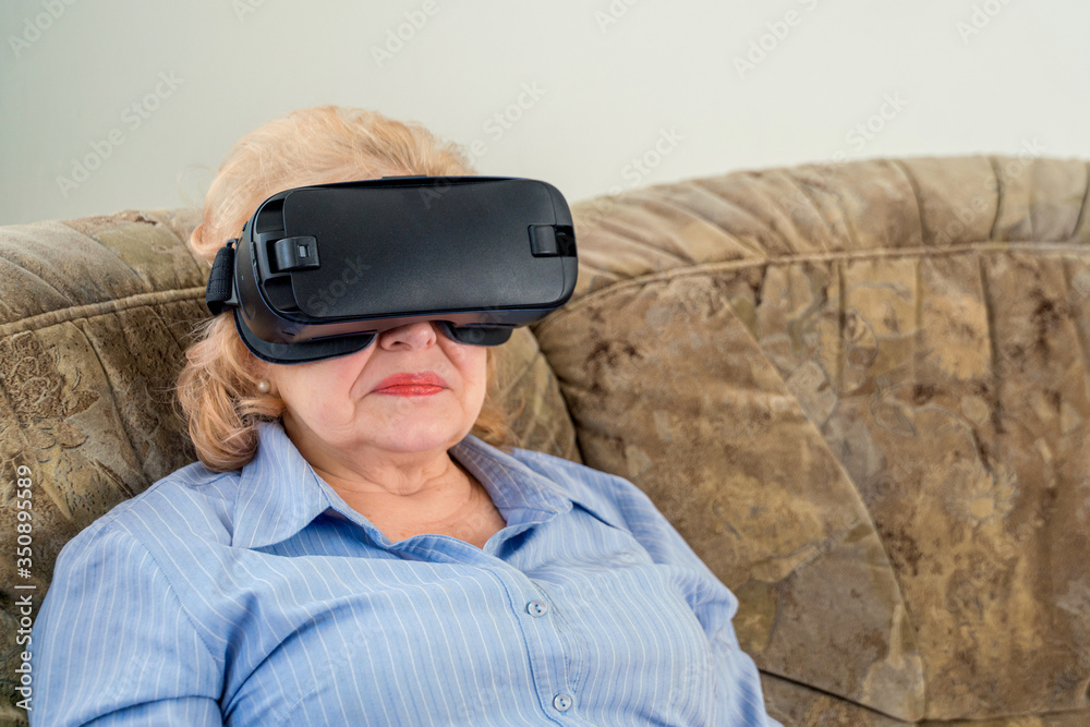 Amazed senior woman enjoying cyber world, using VR glasses at home. New trends and technology concept and funny active elderly Amazed senior woman enjoying cyber world, using VR glasses at home. New trends and technology concept and funny active elderly