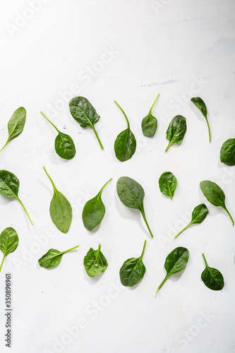 Baby spinach leaves on white surface