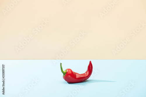 fresh red chili pepper on blue surface isolated on beige